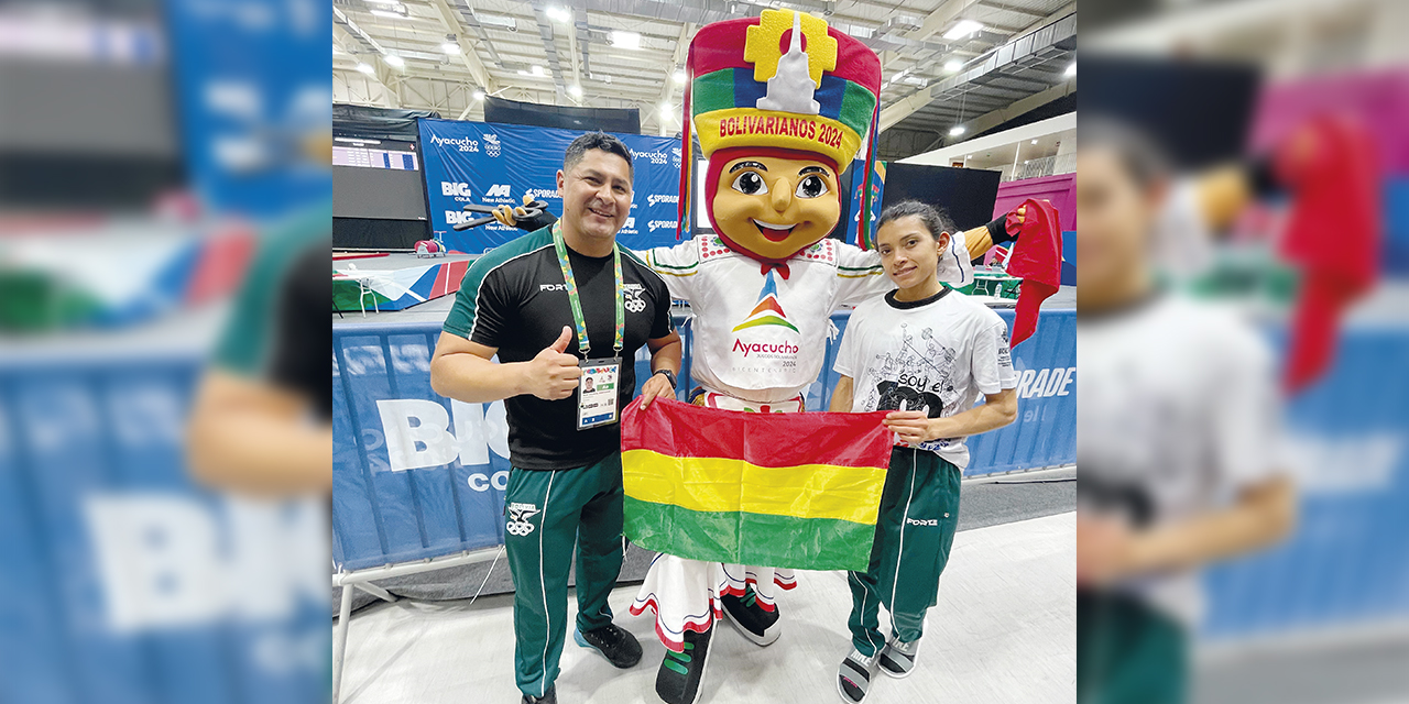Tórrez (d.) posa con la bandera boliviana al lado de su entrenador y la mascota de los Juegos.