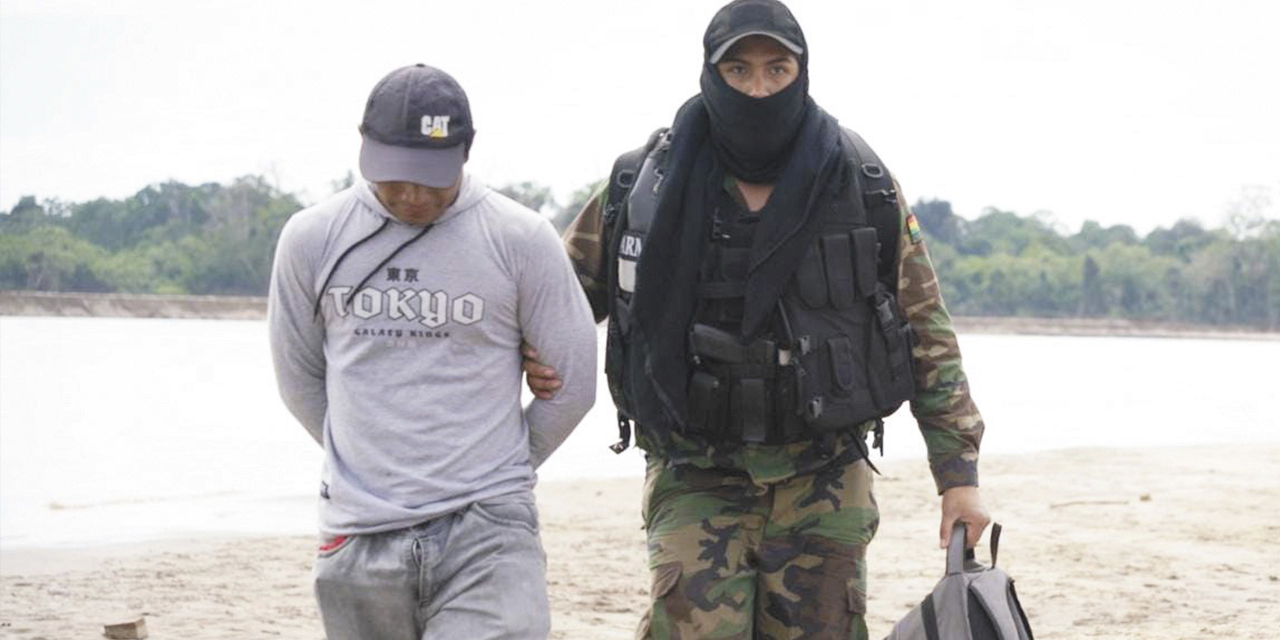 Efectivo policial traslada a uno de los aprehendidos dentro de las dragas.
